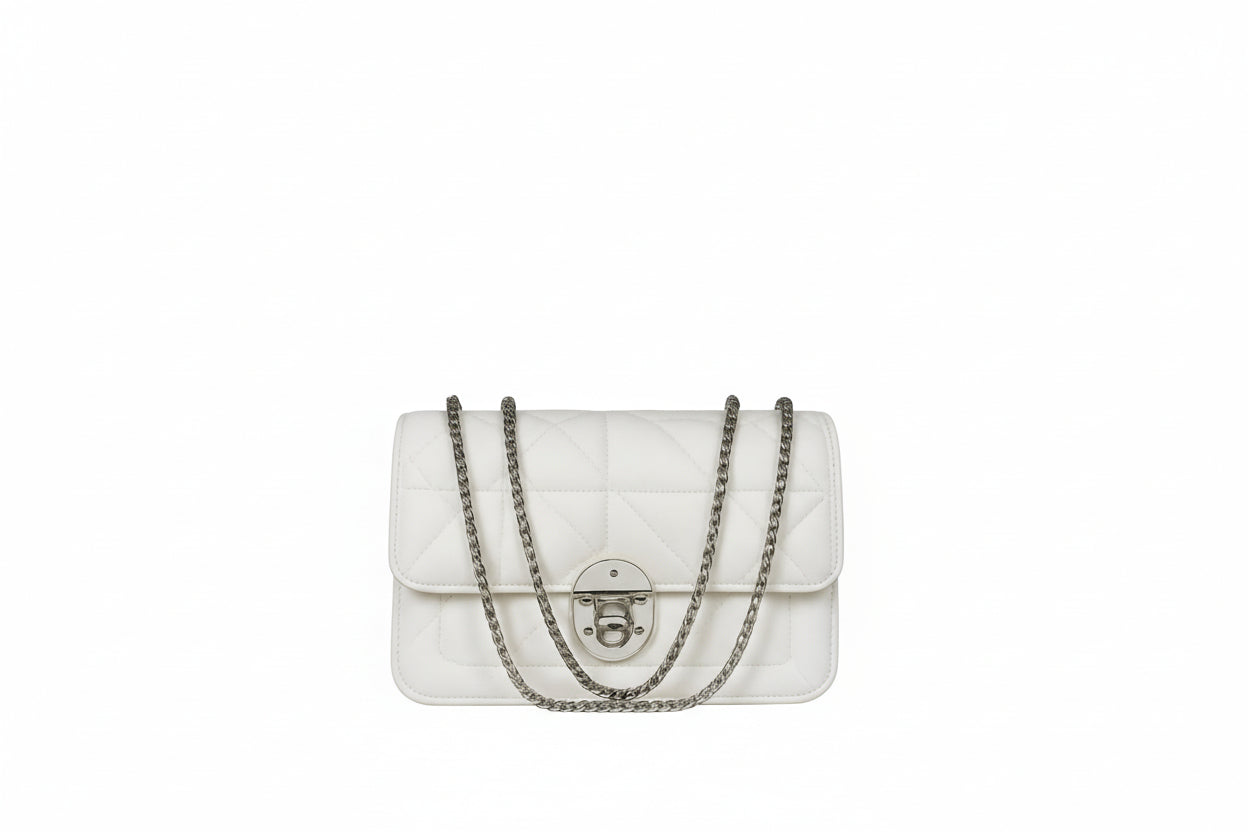 White quilted handbag with a chain strap on a white surface against a gray background