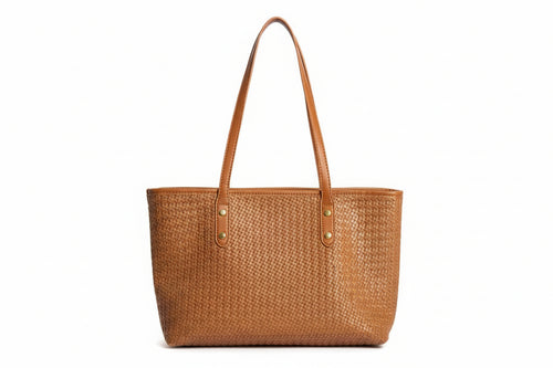 Brown woven handbag held by a person wearing a red and white striped shirt and brown pants.